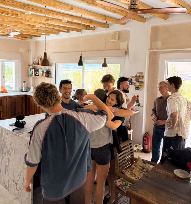 Group hug in a sunlit residency kitchen